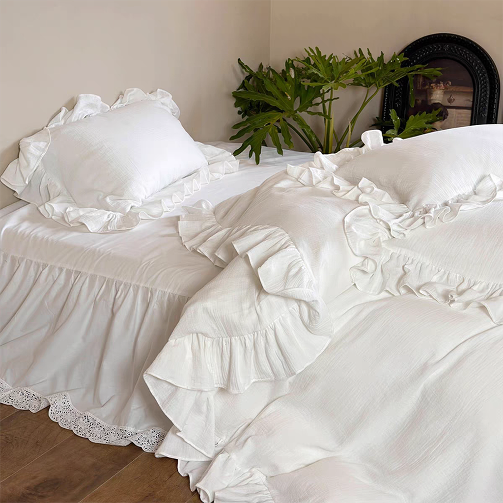 White cotton bedding with layered ruffles and a lace-trimmed bed skirt