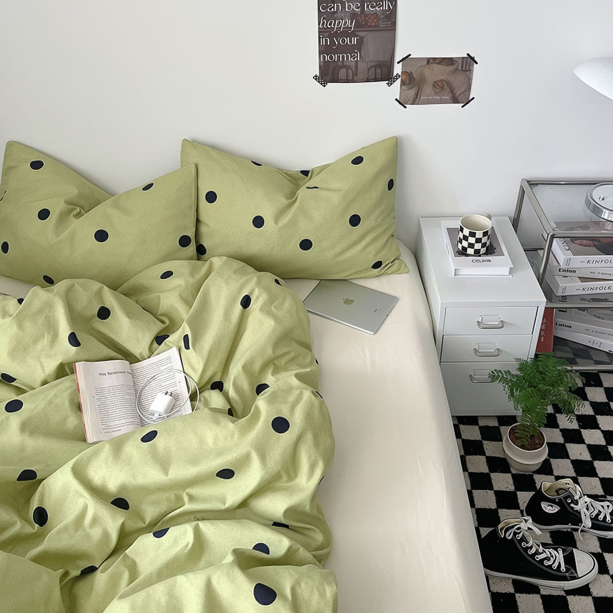 Sage green bedding with dark polka dots styled in a bright bedroom