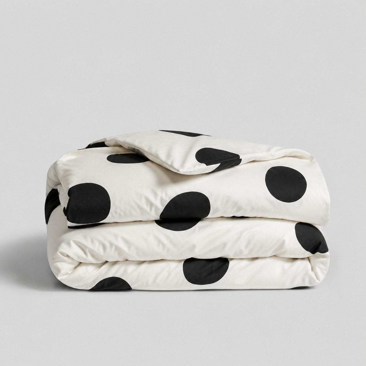 Cream cotton bedding folded with large black polka dots